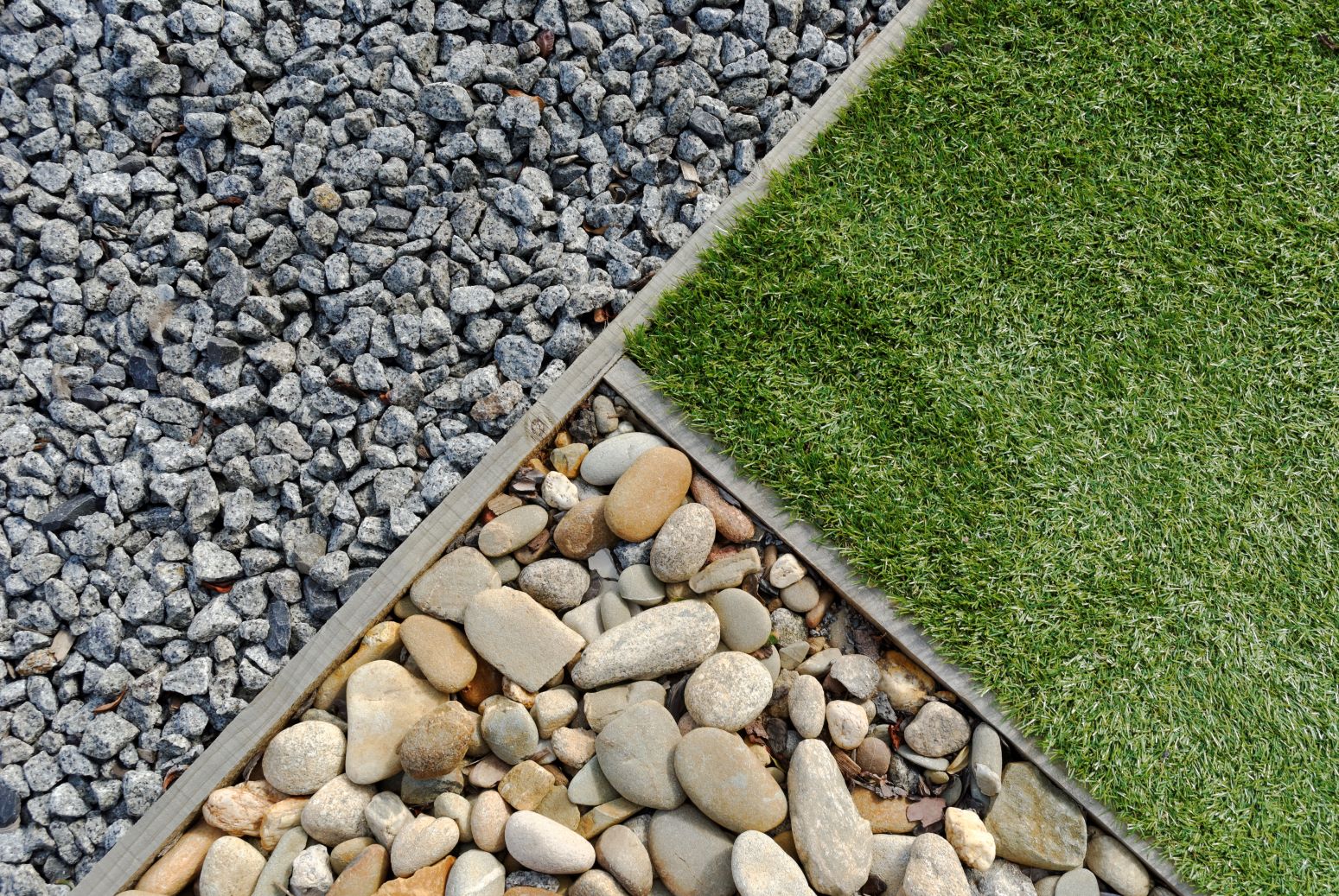 Three pieces of landscaping in one image: shale rocks, river rocks, and grass