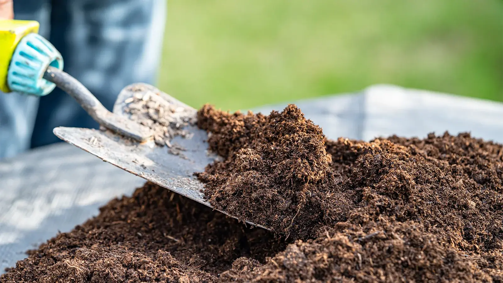 a hand shovel being used to pick up some topsoil
