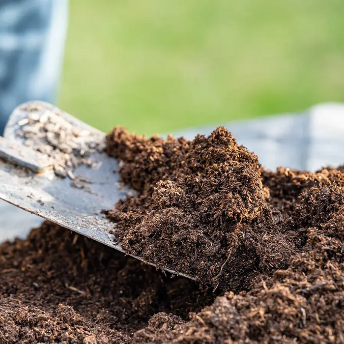 a hand shovel being used to pick up some topsoil