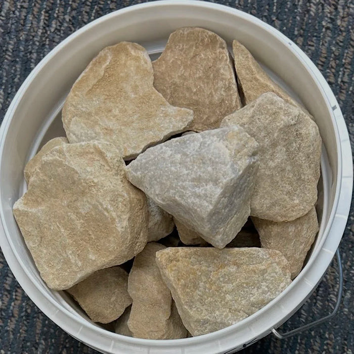 Bucket filled with large beige stones on a textured surface