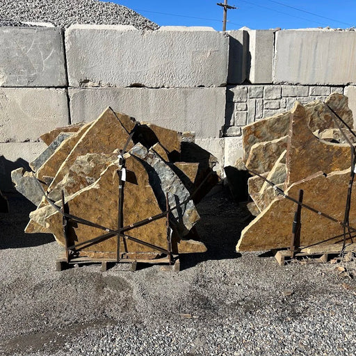 Stack of large stone slabs on a pallet against a wall of concrete blocks.