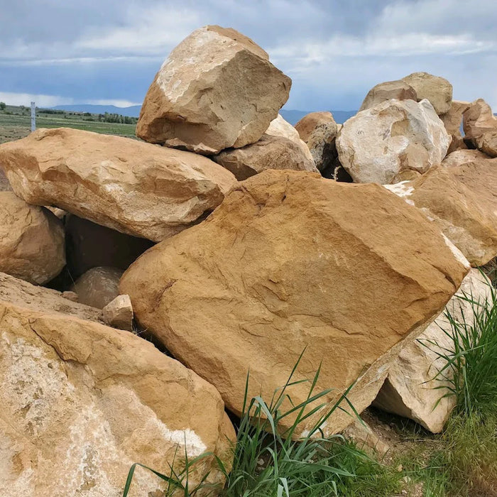 Large brown stones with grass in the foreground and a cloudy sky in the background
