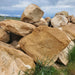 Large brown stones with grass in the foreground and a cloudy sky in the background