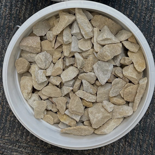 White container filled with small beige stones on a dark textured surface